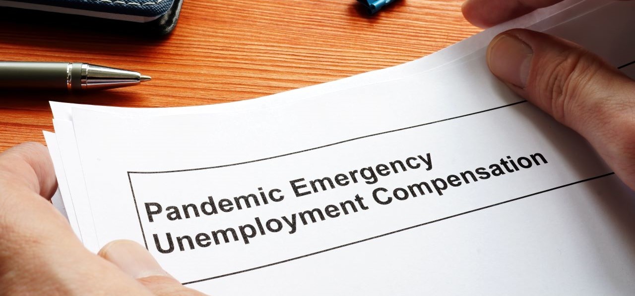 hands on desk picking up pandemic emergency unemployment packet