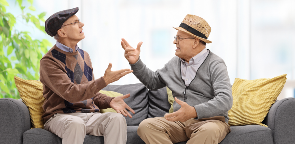 two older gentlemen sitting on a couch arguing about something