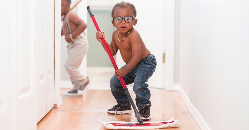 a boy in glasses is mopping a hallway