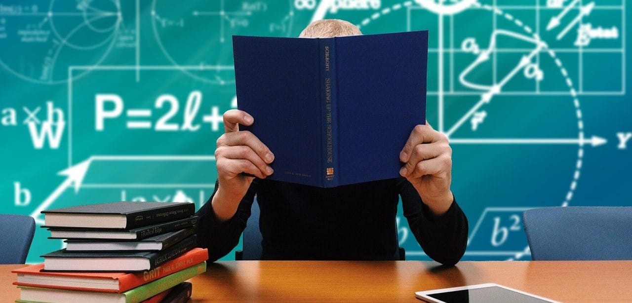 student holding book in front of face