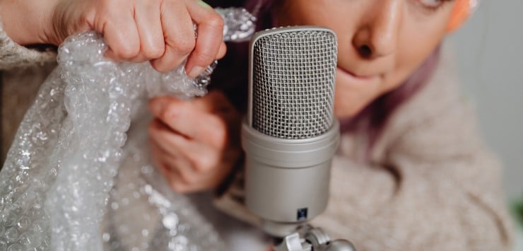 woman crinkling bubble wrap by a microphone for ASMR